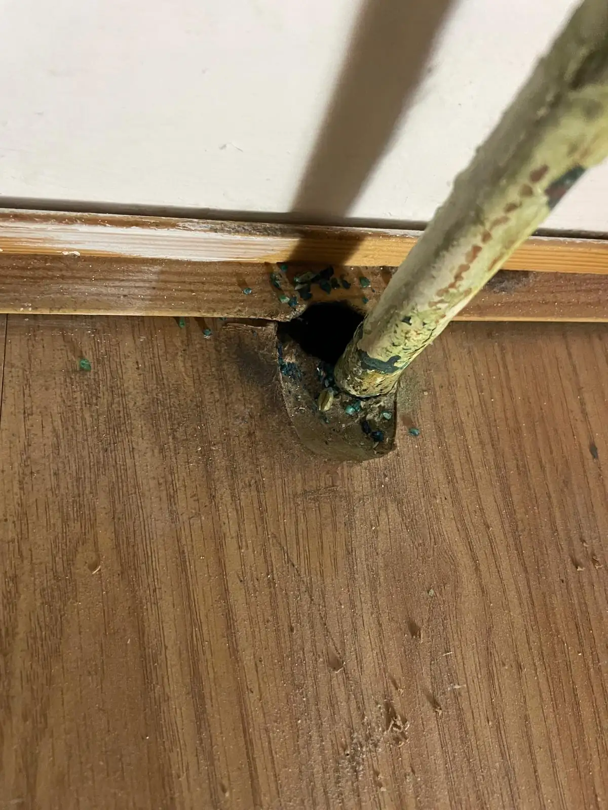 Gnaw marks and damage around a pipe entry point caused by mice